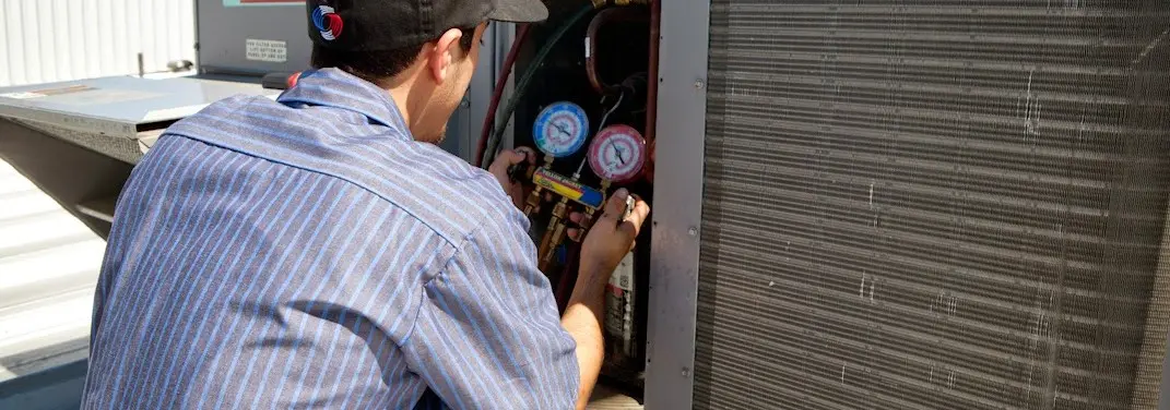 HVAC technician servicing a condenser unit in Seward